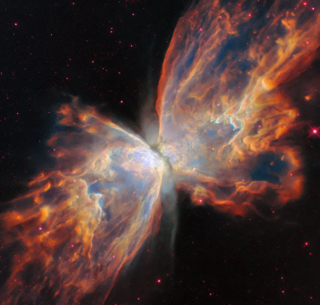 Hubble Space Telescope image of the Butterfly Nebula (NGC 6302), showing two vast orange-and-blue wings of glowing gas separated by a dark central dust lane