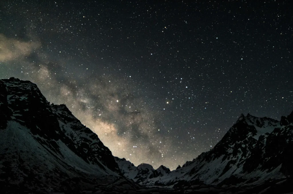 Milky Way visible above dark mountain peaks under a clear star-filled night sky