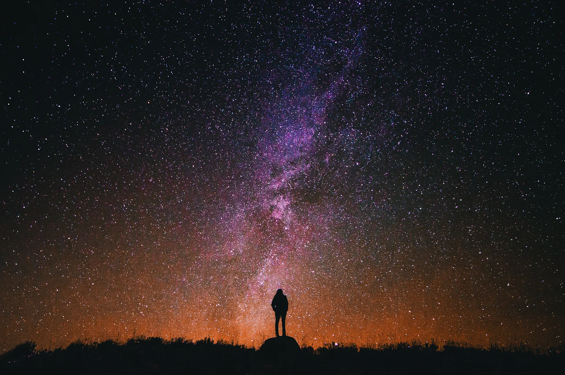 Person silhouetted beneath the Milky Way in a clear star-filled night sky
