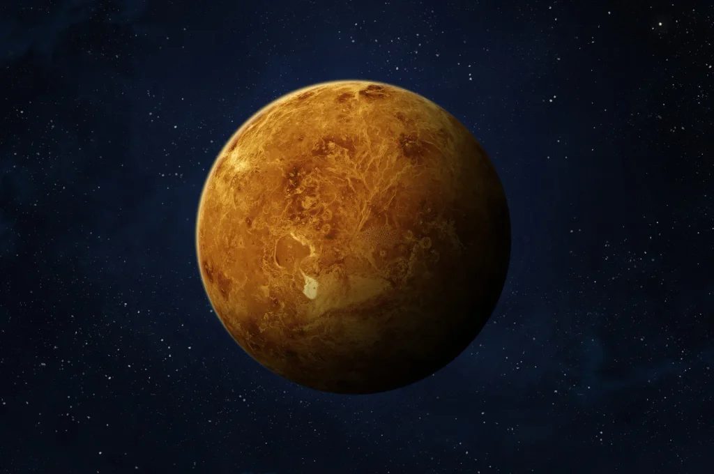Venus showing its yellow-orange cloud-covered surface against a star-filled background