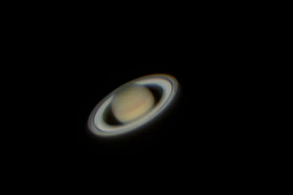 Saturn and its rings seen through a telescope against a dark night sky